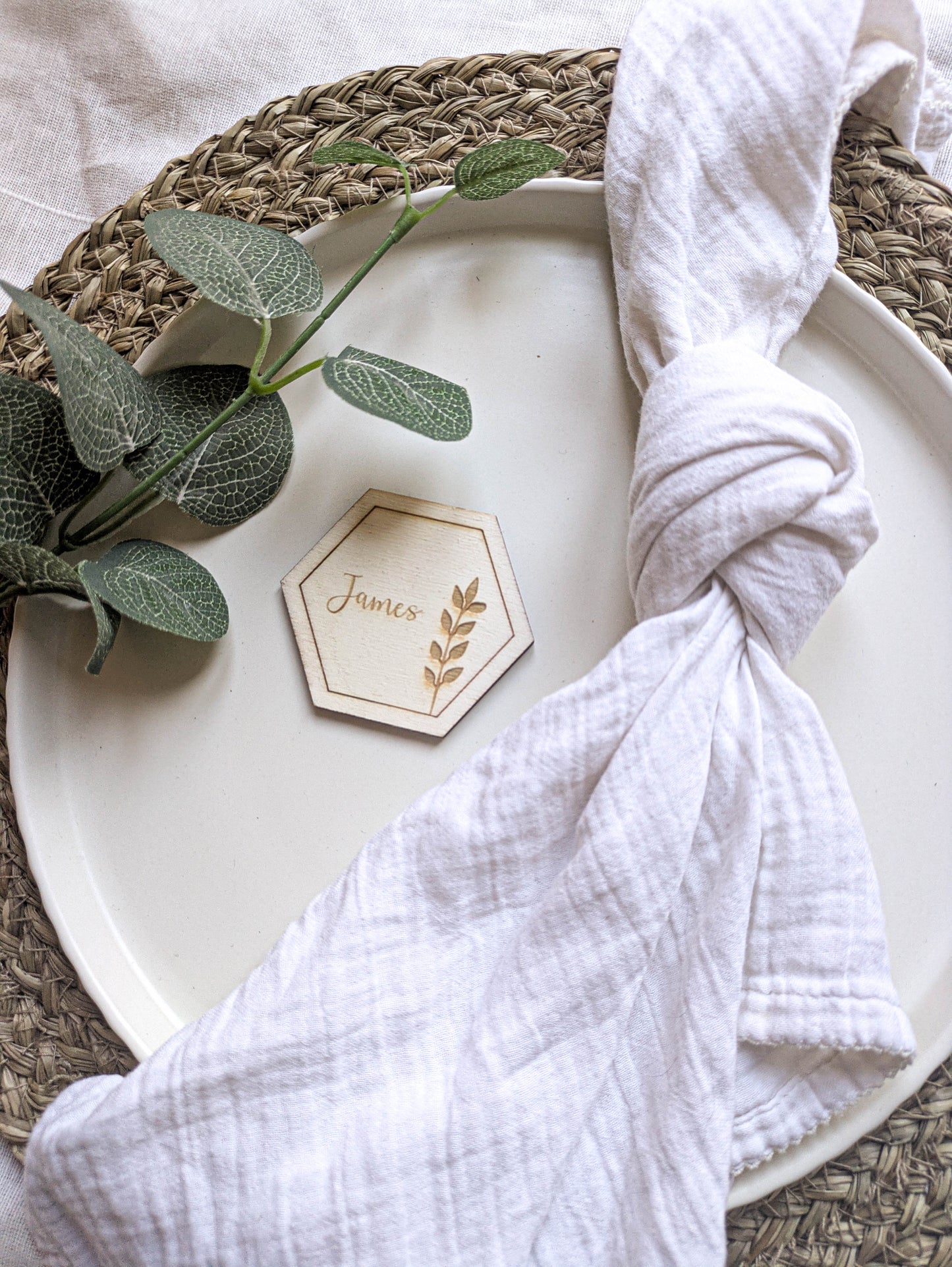 Boho wooden hexagon wedding place setting with napkin and natural foliage