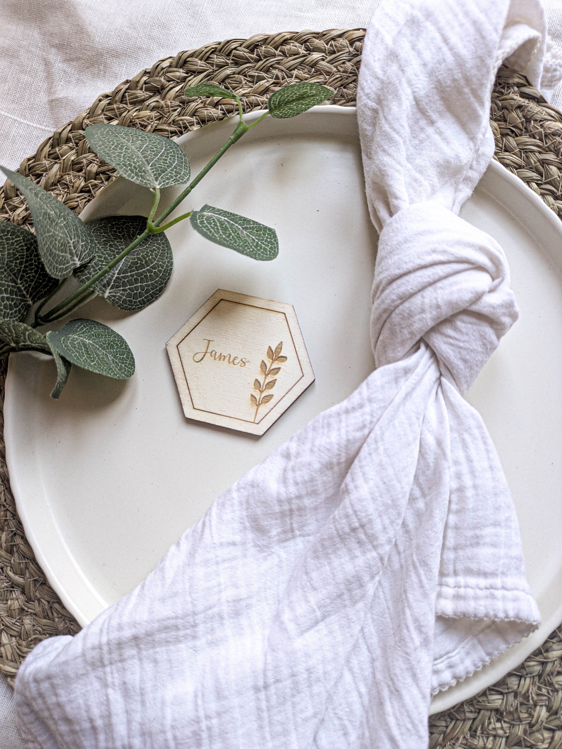 Boho wooden hexagon wedding place setting with napkin and natural foliage
