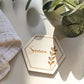 Close up of engraved wooden hexagon wedding place card with botanical detail