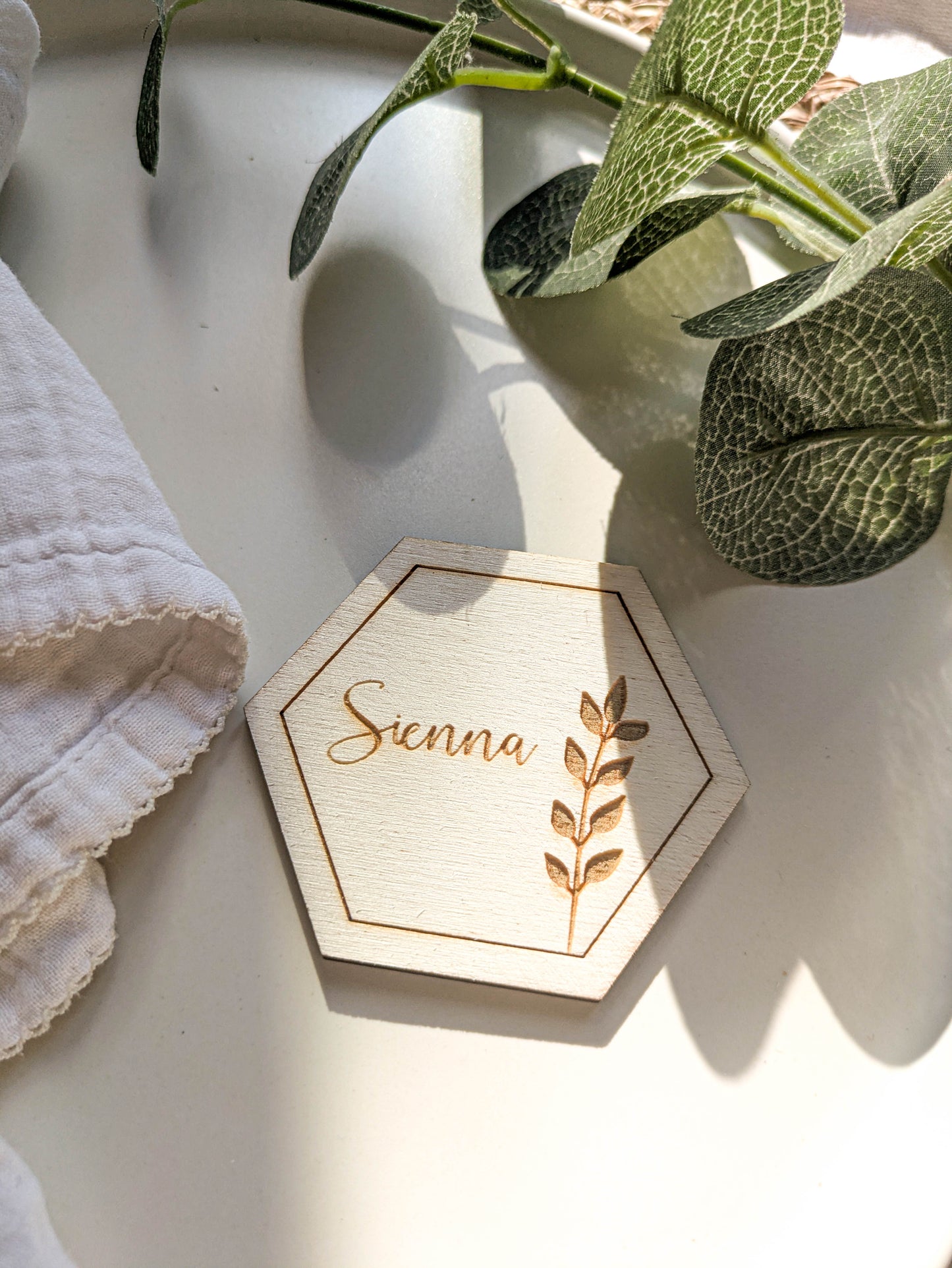 Close up of engraved wooden hexagon wedding place card with botanical detail