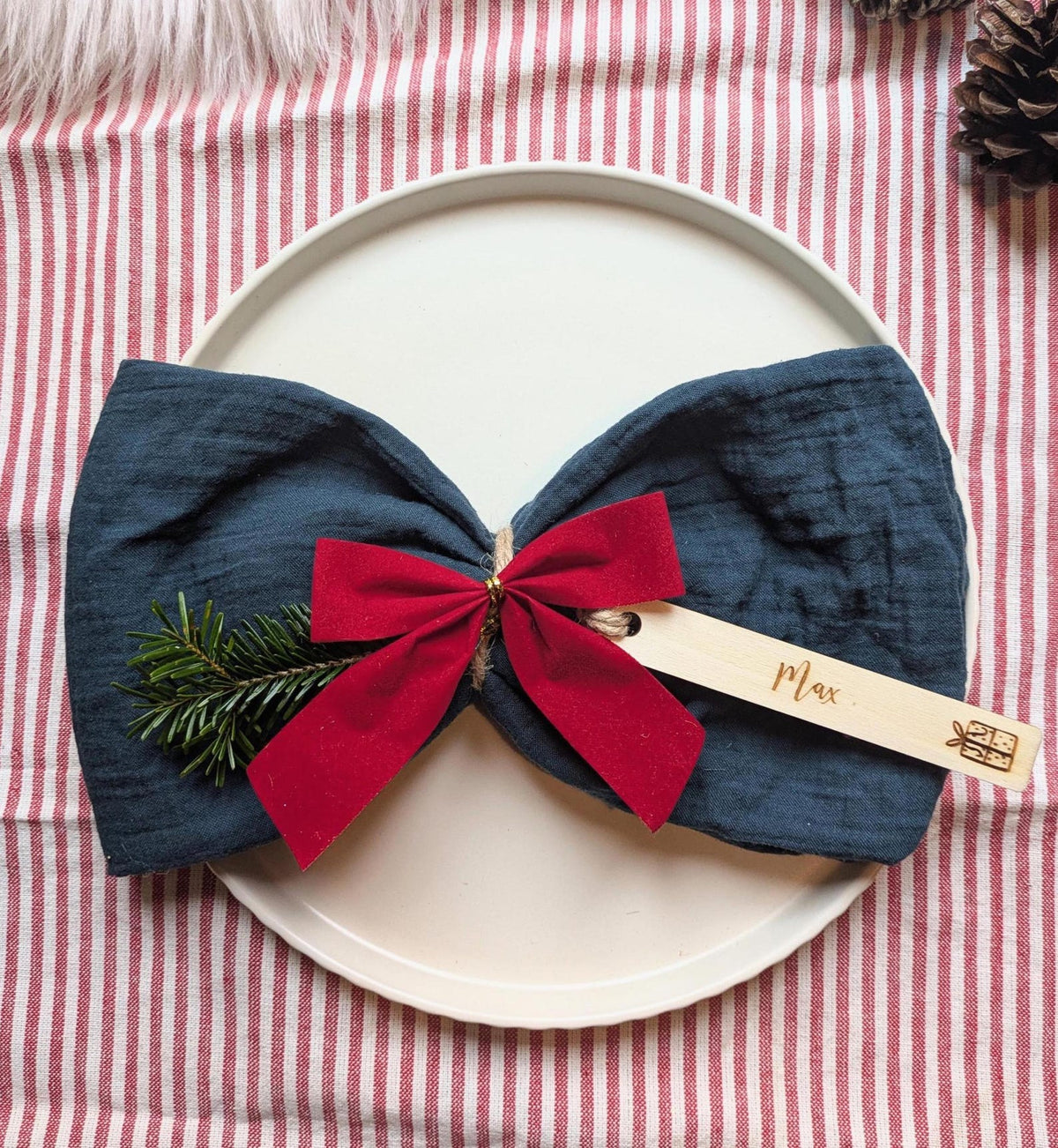 Personalised wooden Christmas present place name styled in a festive table setting; accessories not included