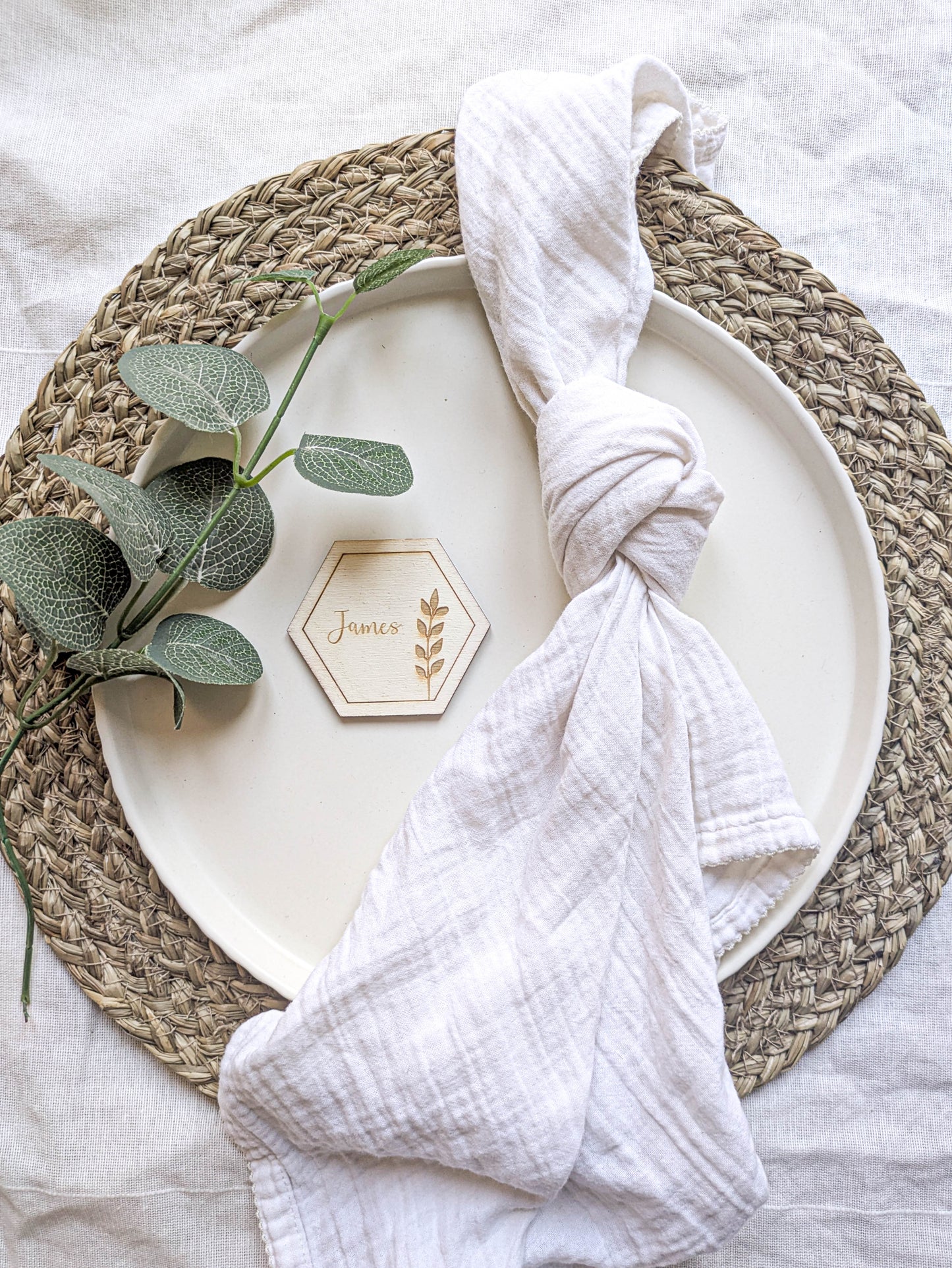 Wooden hexagon wedding place name styled on a plate with a white napkin